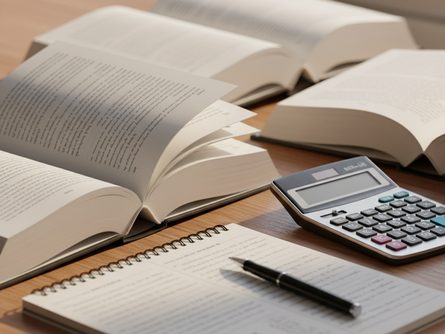 책상 위에 펼쳐진 부동산 투자 서적 여러 권과 노트, 펜, 계산기가 놓여 있는 모습